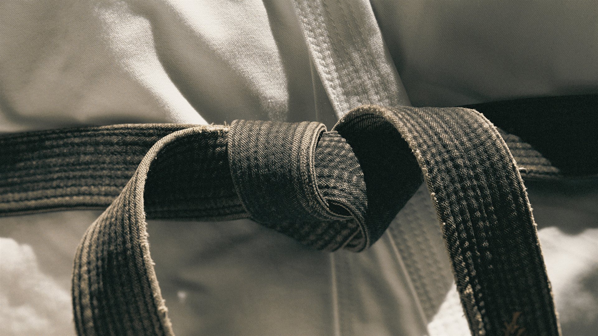 Worn black belt tied over a white karate gi